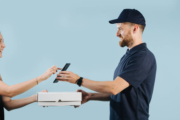 Woman is accepting a box delivery from a courier by signing on a smart phone - Valokuva, kuva