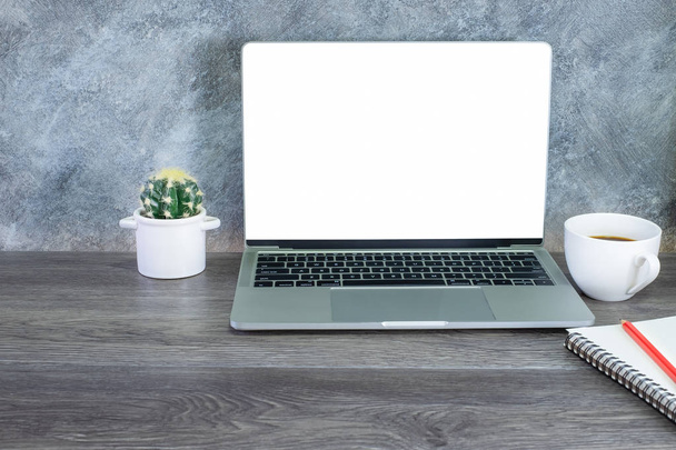 Lugar de trabajo con computadora portátil pantalla en blanco y café taza blanca, lápiz, portátil en la mesa de madera en casa u oficina. con espacio de copia
. - Foto, imagen