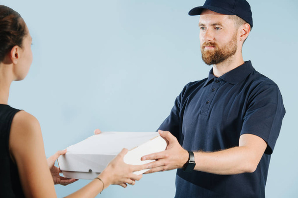 Woman is accepting a box delivery from a courier, taking it from him - Photo, image