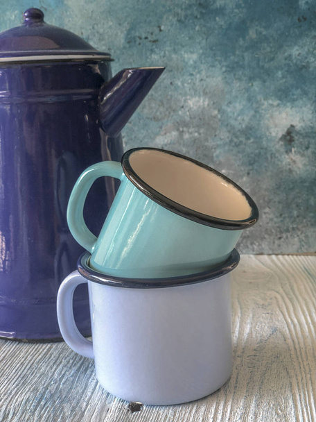 голубой цветной эмали чайник и кружки на деревянный стол
 - Фото, изображение