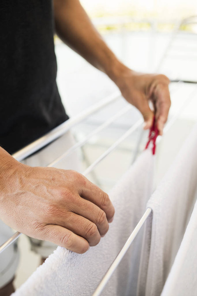 hombre colgando ropa en un rac secado
 - Foto, imagen