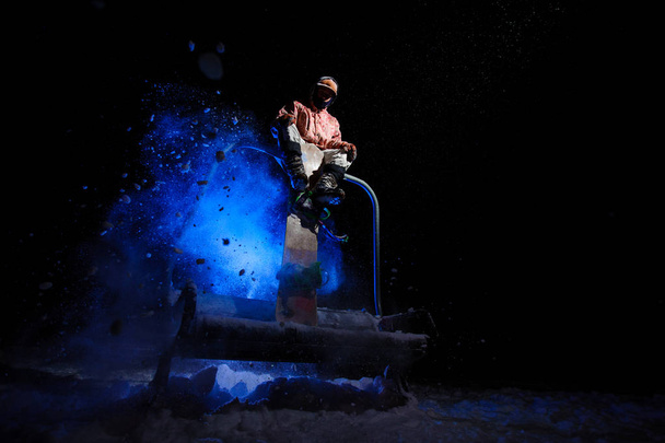 Man snowboarder dressed in a white and pink sportswear sitting on the funicular seat - Fotó, kép