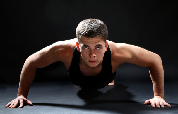 Handsome young muscular sportsman, on dark background - Фото, изображение