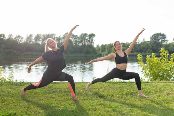 Healthy lifestyle and harmony concept - Young girls doing yoga outdoor - Photo, Image