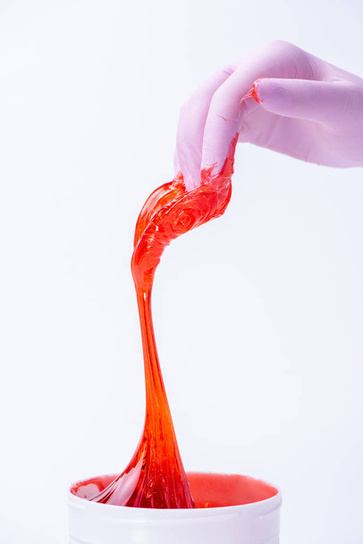 Woman's hand in a glove holds red sugar paste or wax for depilat - Foto, immagini