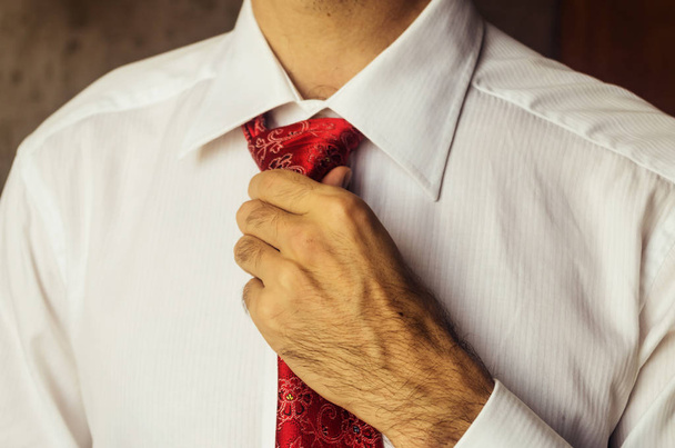 Adam güzel bir kırmızı kravat ayarlıyor. Ciddi bir toplantıya hazırlanıyor. Ofiste kıyafet kuralı. Sabah ritüeli. - Fotoğraf, Görsel