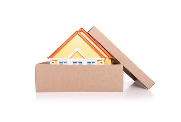 Toy model of a house in a cardboard box on white background. - Zdjęcie, obraz