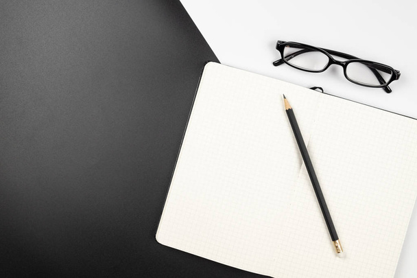 Top view of an empty grid notebook with pencil and eyeglasses - 写真・画像