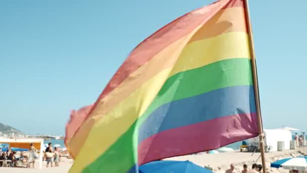 Флаг гордости геев, дующий на ветру на пляже Ситжес, Испания
. - Кадры, видео