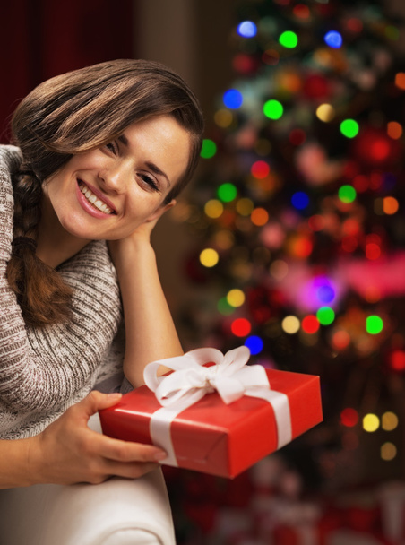Portrait of smiling young woman near christmas tree holding pres - Foto, imagen