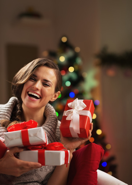 Onnellinen nuori nainen istuu joulukuusen edessä
 - Valokuva, kuva