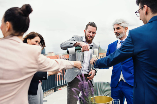Skupina radostných podnikatelů, kteří mají večírek venku na střešní terase ve městě. - Fotografie, Obrázek