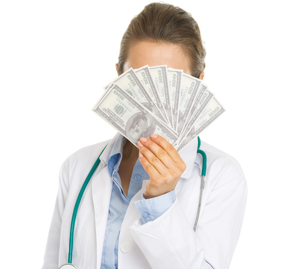 Doctor woman hiding behind fan of dollars - Valokuva, kuva