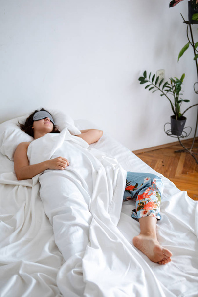 woman sleeping in sleep mask in bed with white sheets - Foto, Imagem