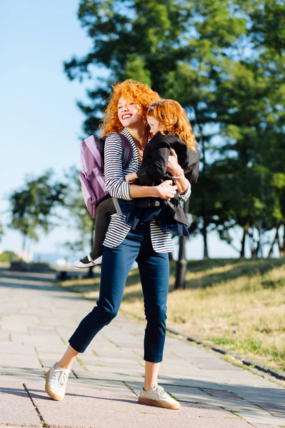 Charming red haired female holding her child - Foto, imagen