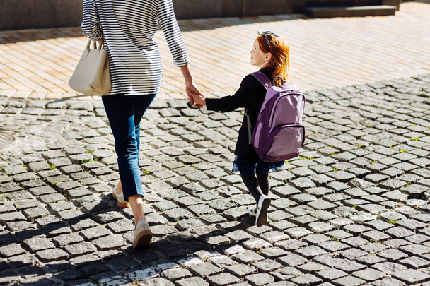 Beautiful schoolgirl holding hand of her mother - Фото, зображення