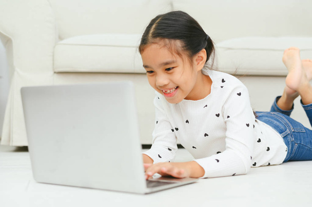 Chica asiática feliz usando el ordenador portátil, concepto para el arte de los niños un
 - Foto, Imagen