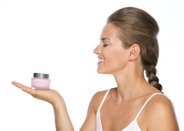 Smiling young woman holding cream bottle - Foto, Imagen