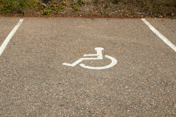 駐車スペースのアスファルトの無効なシンボルサイン。障害者用駐車場の国際マーキング. - 写真・画像