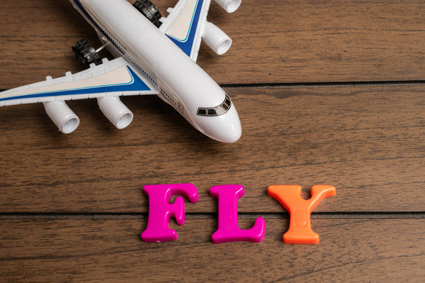 Lelu lentokone ja sana lentää valmistettu värikkäitä kirjaimia puinen tausta
 - Valokuva, kuva