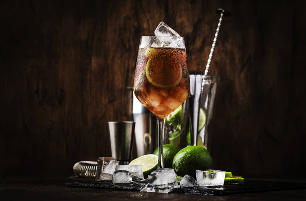 Alcoholic cocktail Long Island with vodka, gin, tequila silver, white rum, liqueur, sugar syrup, lemon juice, cola and ice cubes, vintage bar wooden counter background, selective focus - Foto, immagini