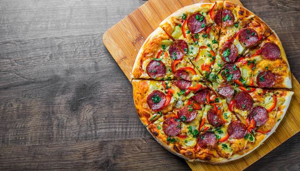 Pepperoni Pizza with Mozzarella cheese, salami, pepper. Spices and Fresh basil. Italian pizza on wooden table background - Photo, Image