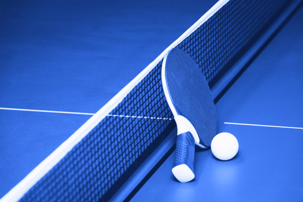 Raquetes e bola na mesa de ténis azul. Actividades desportivas internas
 - Foto, Imagem