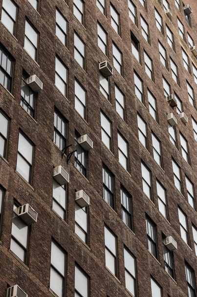 Pystysuora näkymä geometriset yleiset ikkunat ja ilmastointilaitteet teollisuuden tiili rakennuksessa aamunkoitteessa Yhdysvalloissa
 - Valokuva, kuva