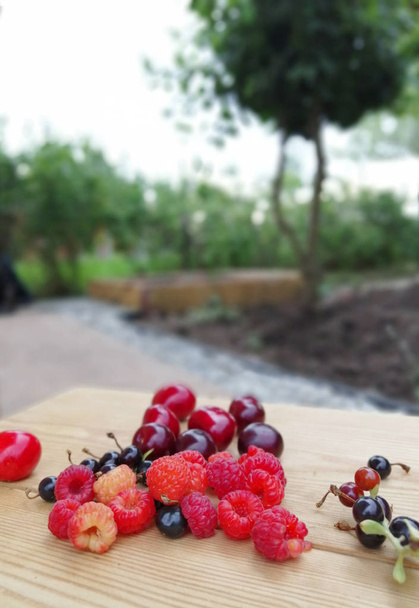 красные ягоды на деревянном столе на открытом воздухе
 - Фото, изображение