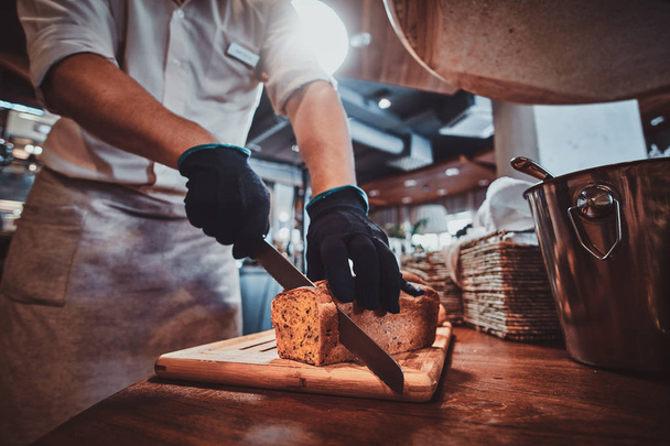 Küchenhelfer schneidet Brot für das Mittagessen - Foto, Bild