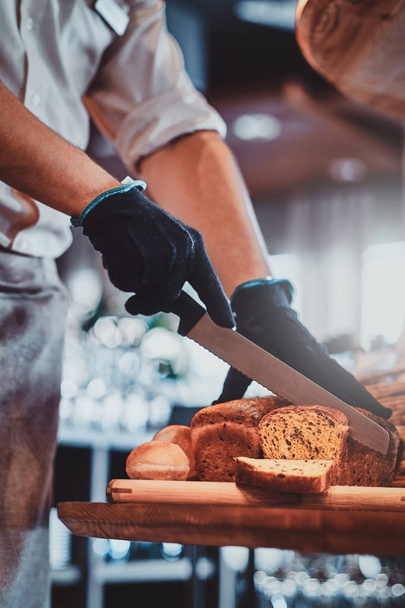 Operaio cucina sta affettando il pane per pranzo
 - Foto, immagini