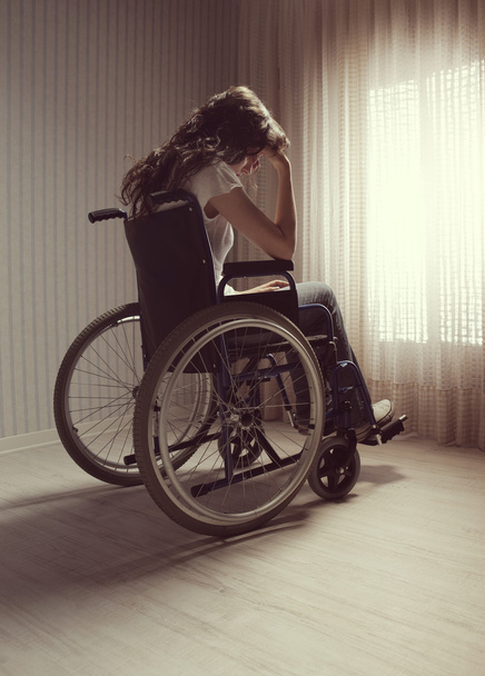 Crying woman sitting in wheelchair - 写真・画像