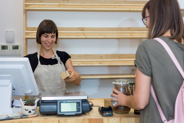 Female shop assistant serving a customer at a desk. - Photo, Image