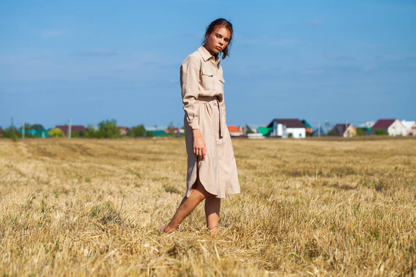 Young beautiful brunette model in a beige dress posing against t - Fotografie, Obrázek
