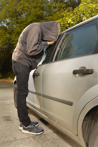 Addicted man in black hooded shirt stealing car - Zdjęcie, obraz