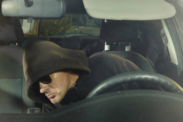 Addicted man in black hooded shirt entering and stealing car - Foto, Bild