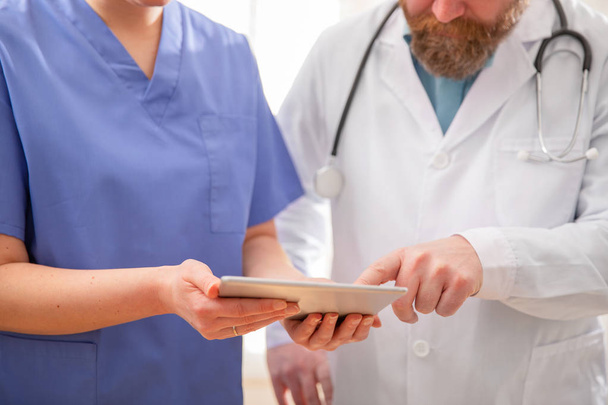 Врач и медсестра обсуждают тестирование пациентов за планшетным компьютером в больнице
 - Фото, изображение
