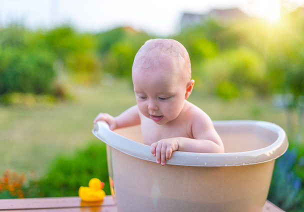 Младенец купается в бане в саду летним вечером. - Фото, изображение