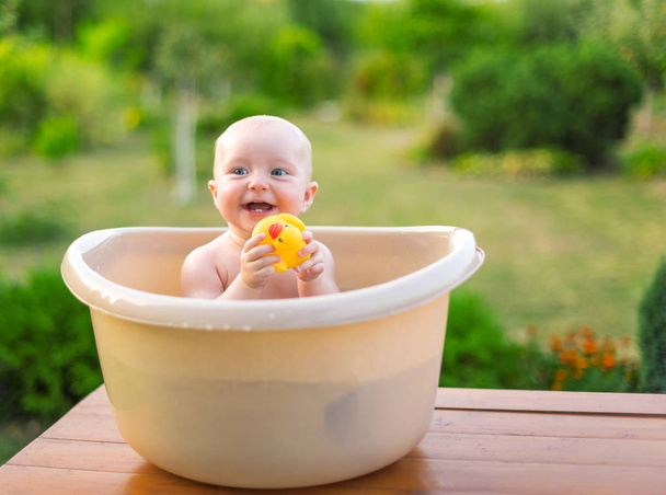 Le bébé se baigne dans un bain dans le jardin un soir d'été. - Photo, image