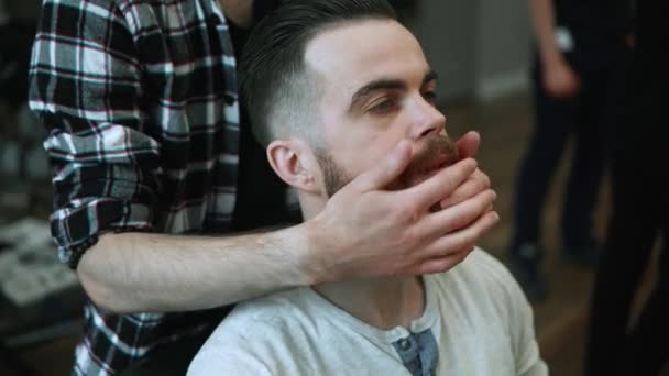 Close-up of barber doing styling with a handsome man with a long beard. Hairdressers hands at working process. Barber making haircut of attractive bearded man in barbershop. Hairdresser at work. - 映像、動画