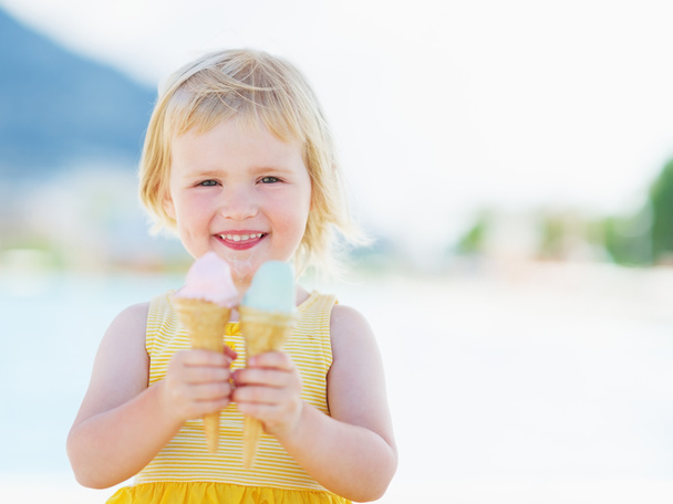 Smiling baby eating two ice cream horns - Fotoğraf, Görsel