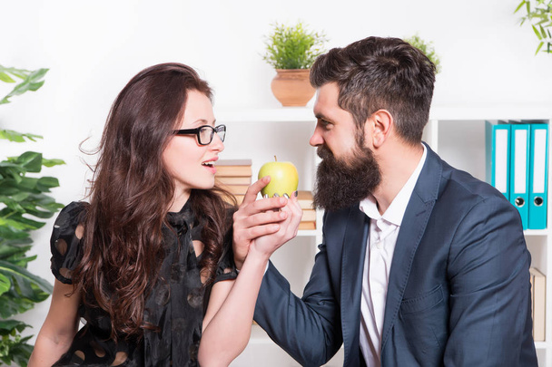 Apple is high in vitamin. Boss and sensual secretary holding vitamin fruit in office. Bearded man and sexy woman with healthy vitamin snack at work. Vitamin food actually works - Photo, Image