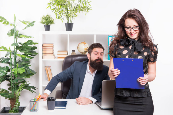 Charming nerd. Sexy female employee with nerd look standing in front of employer. Adorable nerd girl and businessman working in office. Sensual secretary wearing nerd glasses and bearded boss at work - 写真・画像