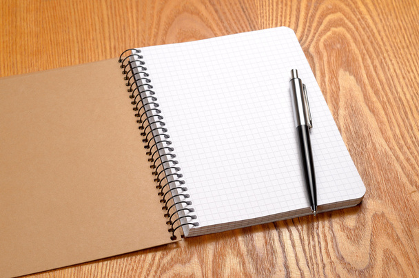 A white note book with black pen on wooden table - Photo, image