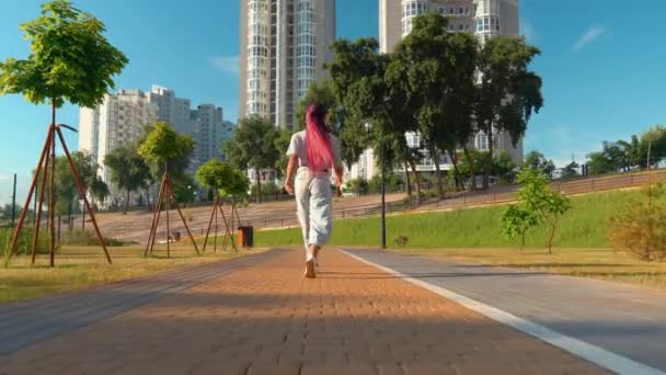 uśmiechnięta African American kobieta spacery w słoneczny dzień chodnik - Materiał filmowy, wideo