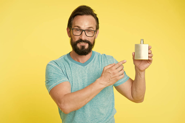 Amazing benefits of using perfumes. Man bearded handsome hold bottle perfume. How choose perfume for men according to occasion. Make sure smell fresh throughout day. Wearing perfume is enhancing mood - Фото, изображение