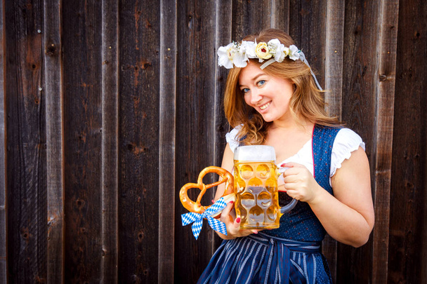 beautiful young woman holding glass of beer with pretzel and looking at camera - Foto, Imagem