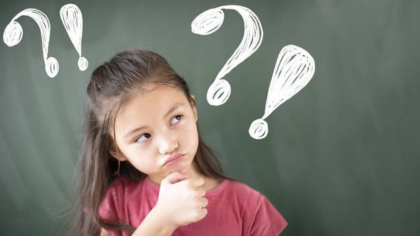  little girl standing against chalkboard with question mark - Photo, image