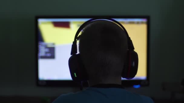 Chlapec ve sluchátkách přehrává večer hru online - Záběry, video