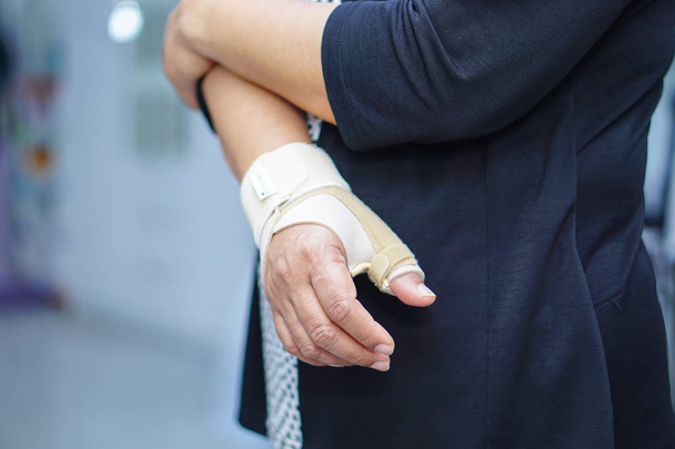 Ázsiai középkorú hölgy nő használja elasztikus kötés kezelésére de Quervain szindróma kéznél és az ujj hivatalban. - Fotó, kép